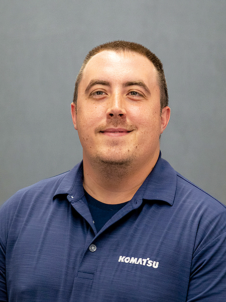 An image of Tommy Hergenreder, North American Manager, Digital Product at Komatsu, wearing a blue Komatsu button-up shirt.