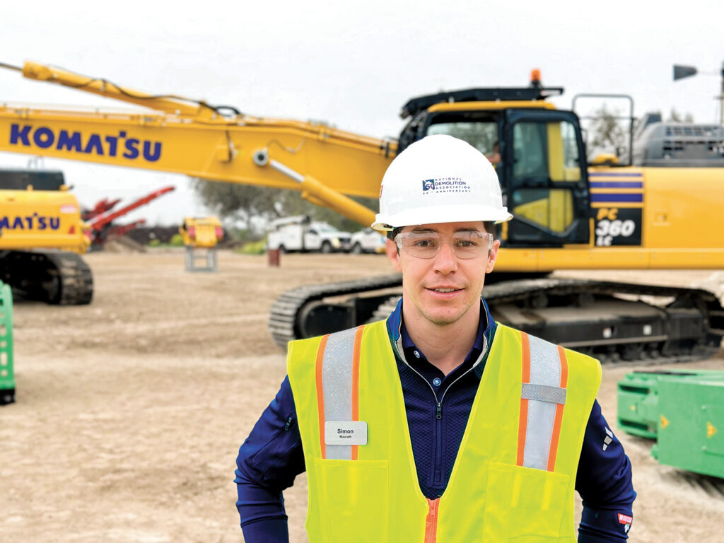 An image of Simon Maurath, Sales Representative at Lehnhoff, wearing a National Demolition Association 50th anniversary hard hat and a reflective vest.