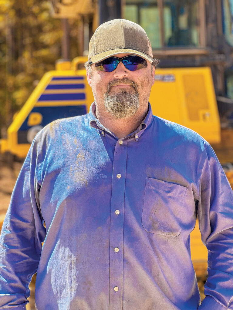 A man wearing a blue long sleeve shirt and a hat, identified as Erick Taunton, Operator at Russell Lands Inc.