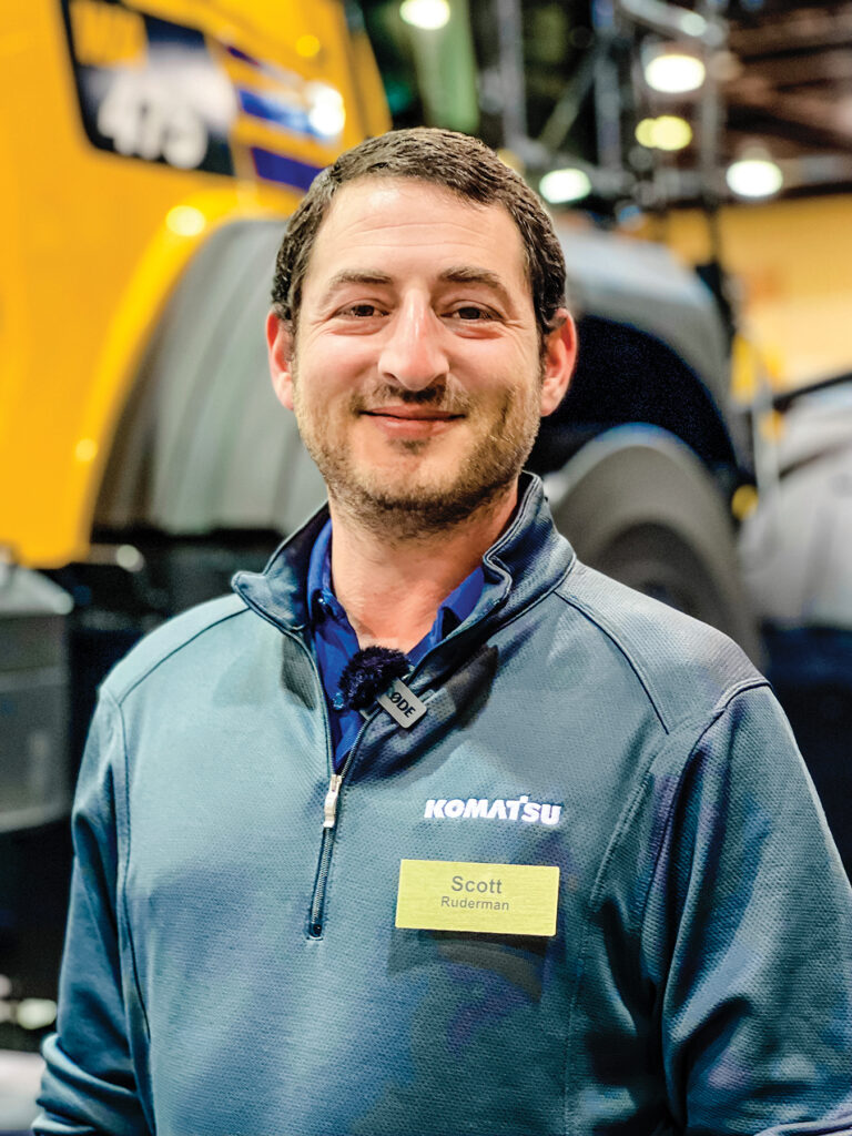 An image of Scott Ruderman, Product Marketing Manager at Komatsu, wearing a Komatsu branded pullover with a name tag.