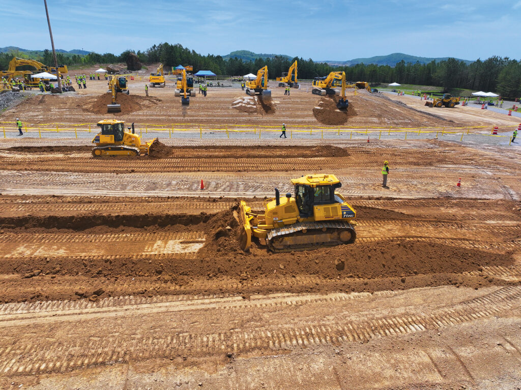 A view of Komatsu dozers, excavators, and people in hard hats and reflective vests at Demo Days.