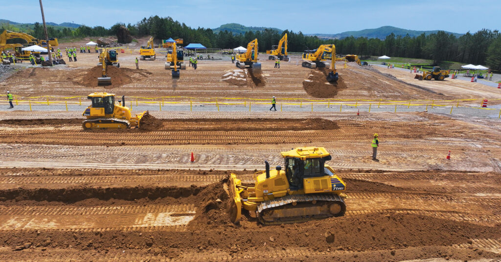 A view of Komatsu dozers, excavators, and people in hard hats and reflective vests at Demo Days.